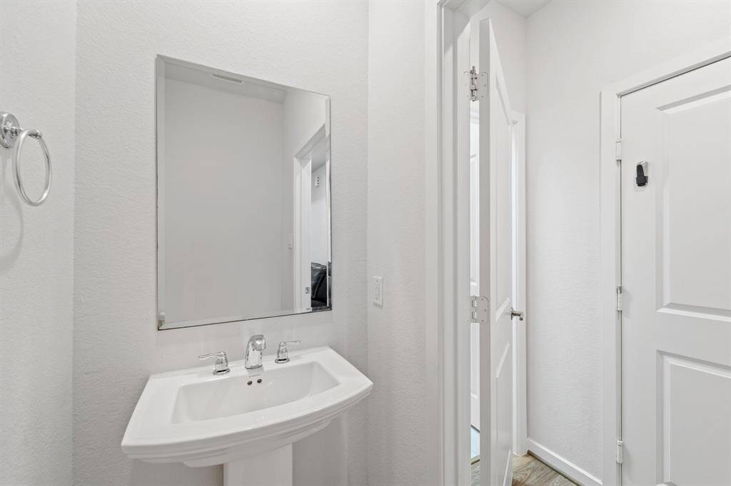 A clean and classic powder room with pedestal sink and sleek mirror—perfectly located for guests on the main floor.