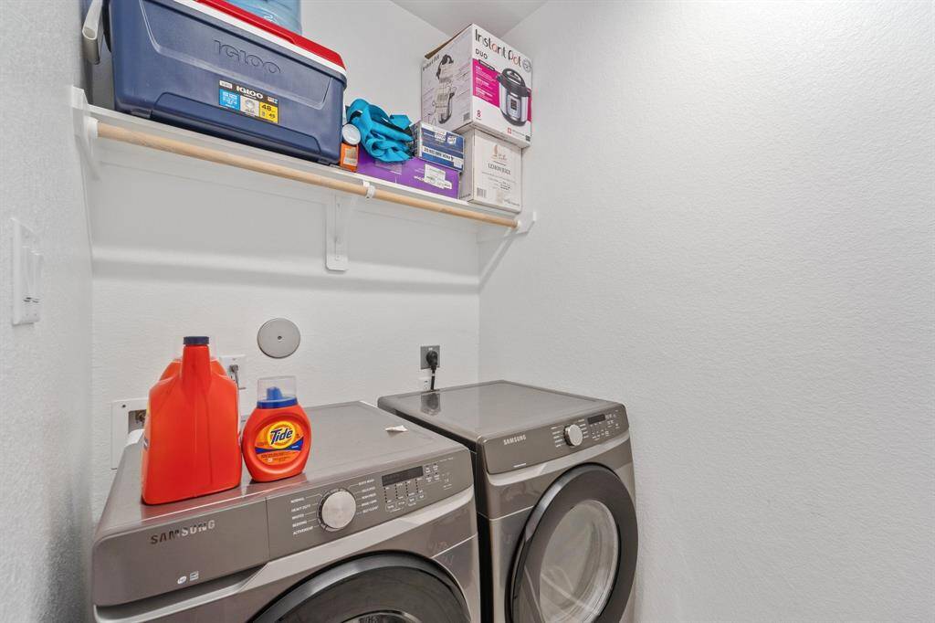 A functional laundry room includes space for a full-size washer and dryer, upper shelving for storage, and plenty of room to stay organized.