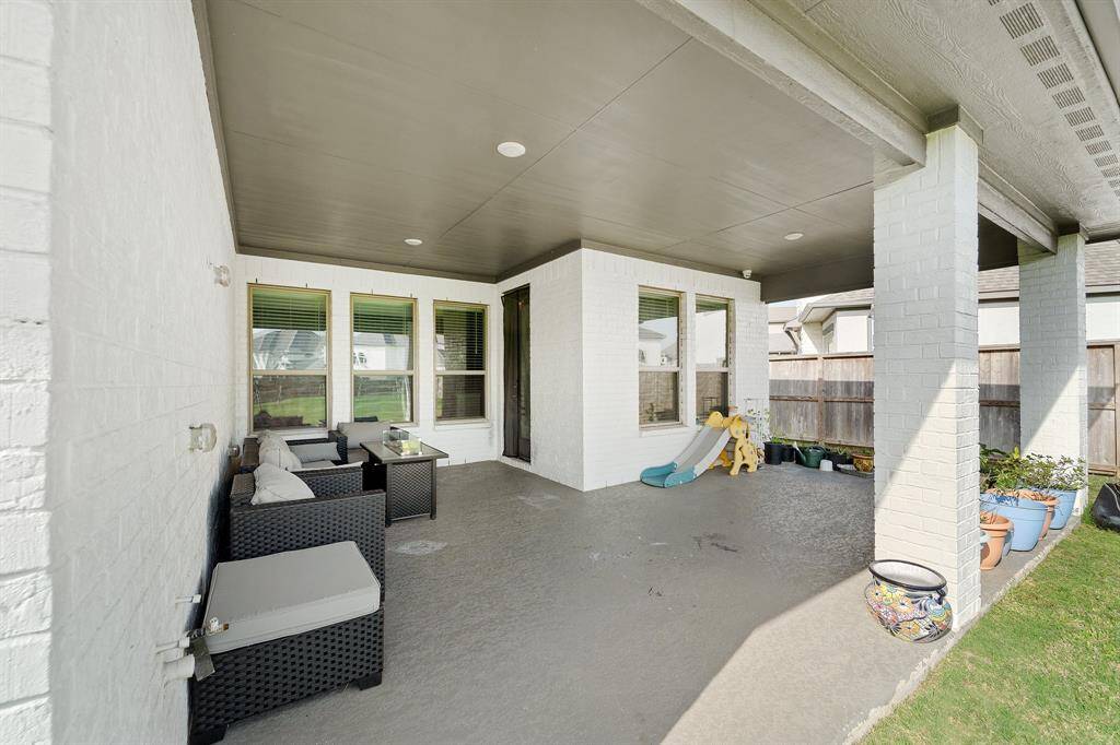 Spacious covered patio with room for both outdoor lounging and play, perfect for relaxing or entertaining in the shade.