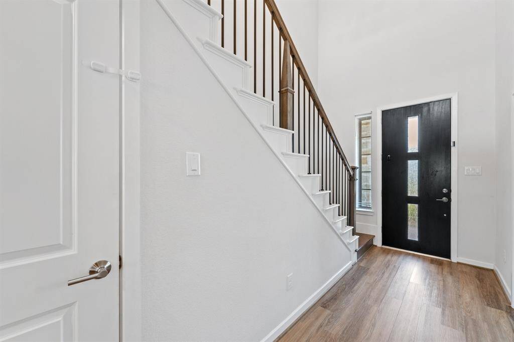 A modern front door with vertical glass insets adds curb appeal, while the bright foyer offers a sleek transition into the heart of the home.
