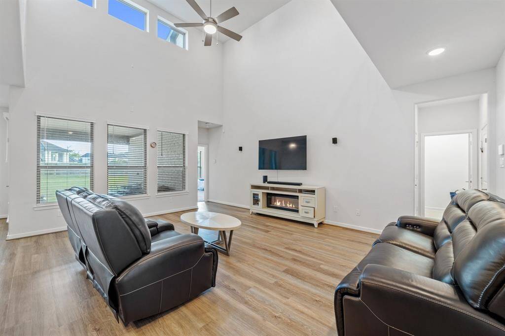 The spacious living room features tall ceilings, a modern ceiling fan for added comfort and tons of natural lighting—perfect for relaxing or entertaining.