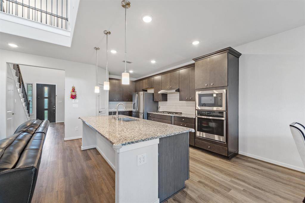Granite countertops, pendant lighting, and dark cabinetry create a sleek and functional kitchen that opens to the main living area.