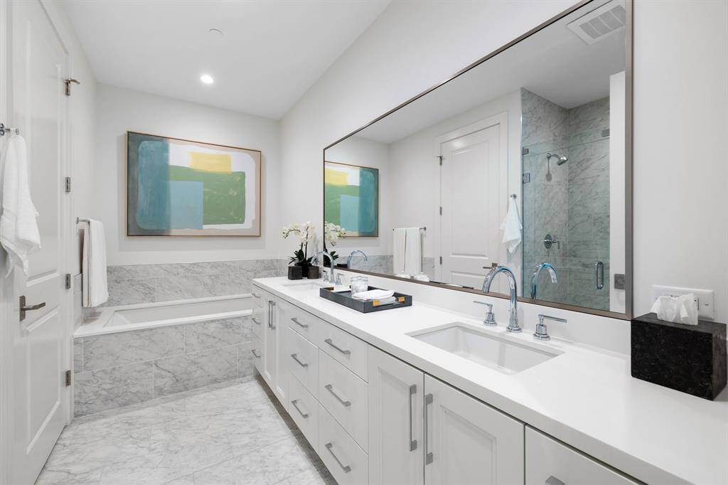 Primary bathroom with dual sinks, quartz counter-top, soaking tub, glass-framed walk-in shower, linen closet, private water-closet and a large walk-in dressing room.