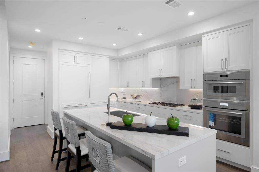 Featuring sleek white cabinetry, elegant quartz countertops, and a marble backsplash.