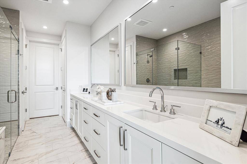 Primary bathroom featuring dual sinks, gorgeous quartz counter-top, glass-framed walk-in shower with shower seat, soaking tub, linen closet and a huge walk-in dressing room