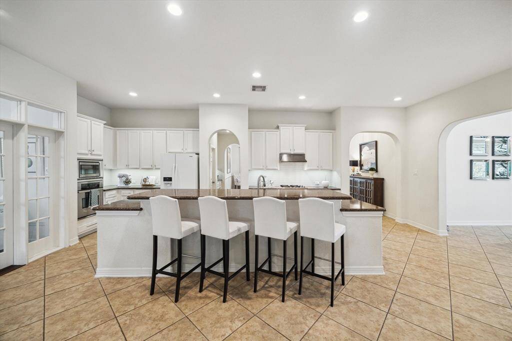 The kitchen features an oversized island that comfortably seats up to six barstools, making it the perfect gathering spot for casual meals or entertaining. With plenty of space to move around, even large families can navigate the area with ease—no traffic jams during breakfast or dinner time.