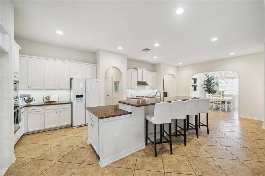 This spacious kitchen is anchored by an oversized island with seating for up to six, offering the perfect blend of form and function. Its open layout allows for easy flow and movement, even when the kitchen is full of guests or family during mealtime.