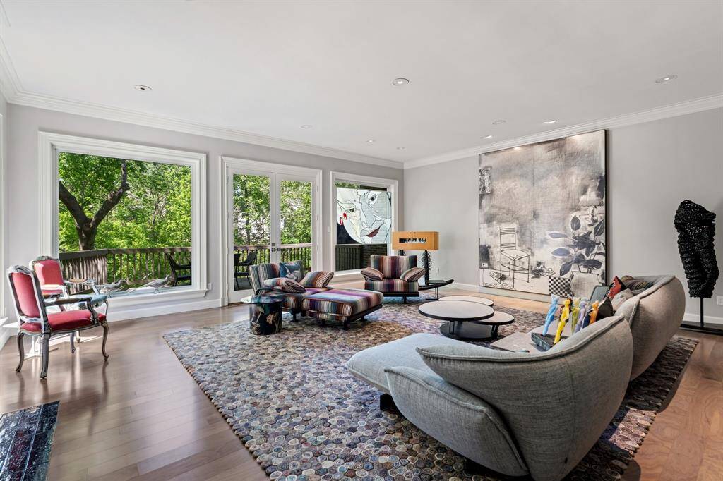 The Living Room standouts include wide planked hardwood floor, double crown molding, and a wood burning fireplace, plus French doors to the balcony. The fireplace is currently tiled over.