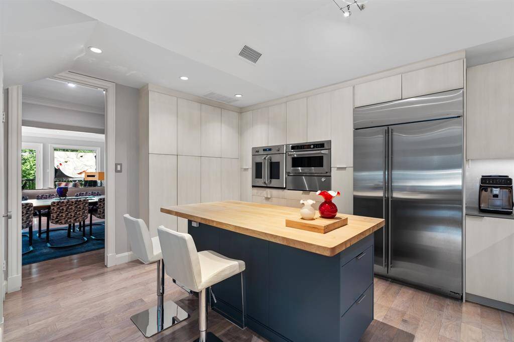 Now this Kitchen is a Chef’s delight with butcherblock island counter, Monogram stainless steel appliances, and custom cabinetry beneath coffered ceilings.