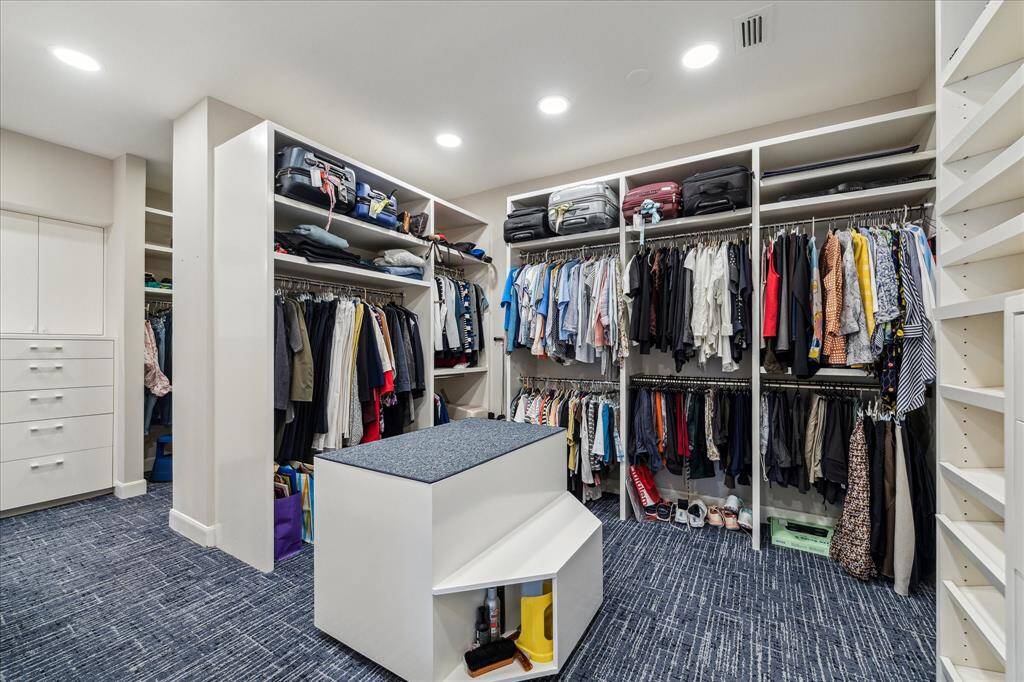 One of two large custom walk-in closets featuring additional drawers, seating area, valet rods, and abundant built-in shelving. There is an exit from this closet to the sitting room so as not to have to exit through the bedroom if someone is sleeping.
