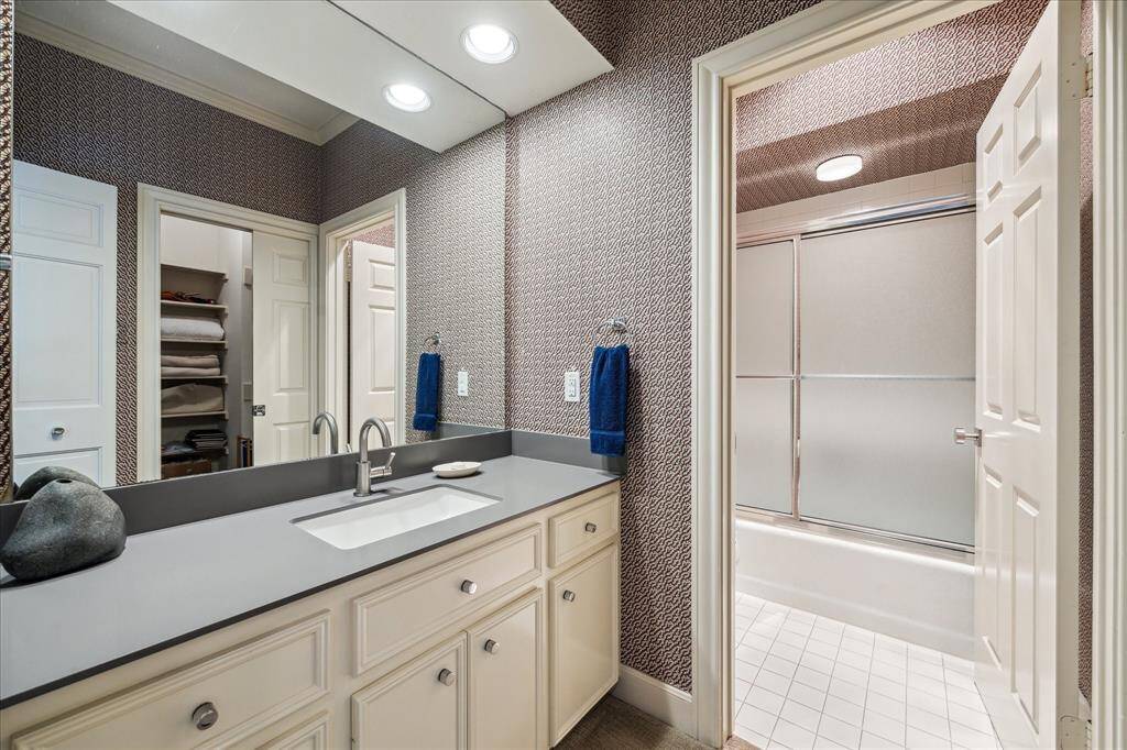 This is the Ensuite bath in Bedroom 2 with designer wallpaper, ceramic tile, undermount sink, and tub/shower in a separate room from the vanity with the toilet..