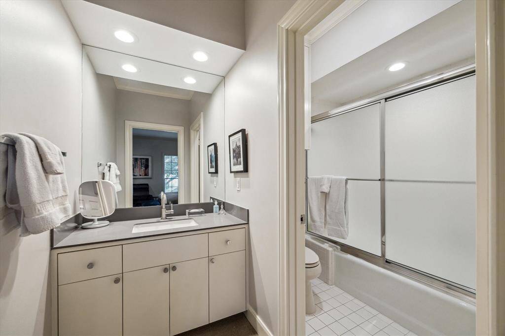 This is the Ensuite bath in Bedroom 3 with private wet area, linen cabinet, tub/shower with ceramic tile surround and glass enclosure.