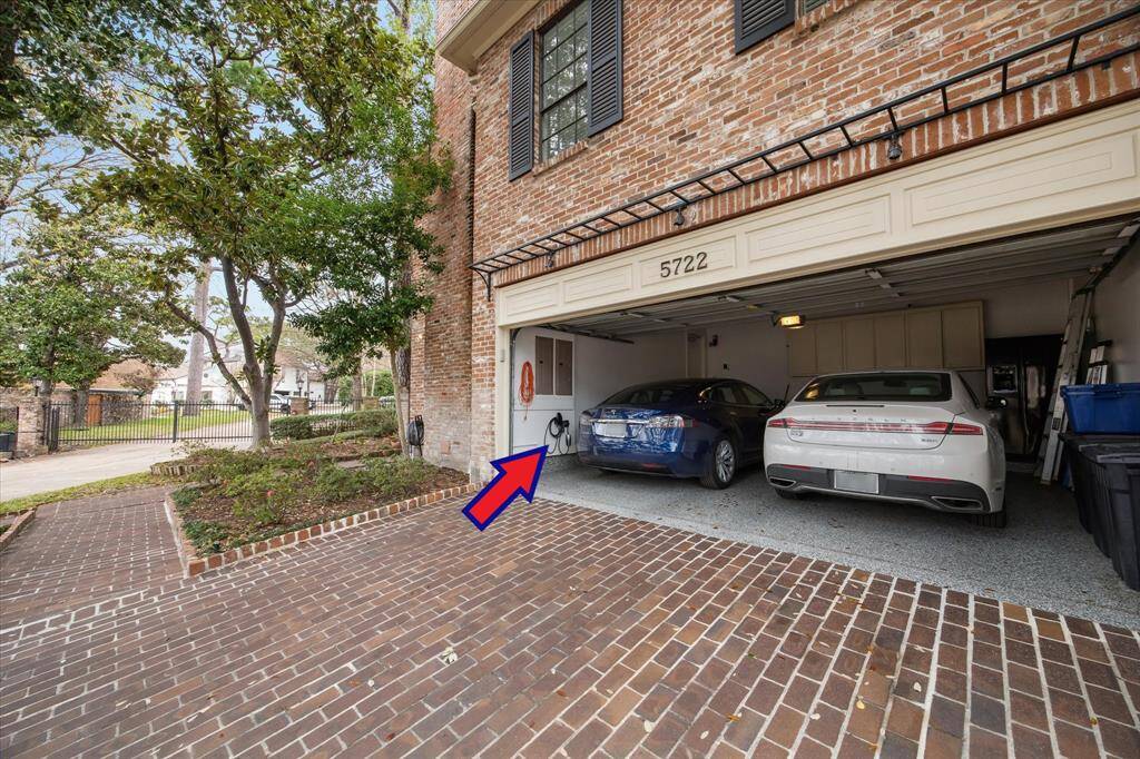 Two-car garage with open doors showcasing ample storage space, easy driveway access, and direct home entry. There is an electric vehicle charger in this garage too.