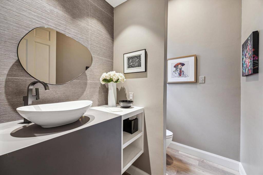 The Powder Bath features wide planked hardwood floor, decorative vessel over mount lavatory, and artistic stained glass window accent. Note the privacy wall too!