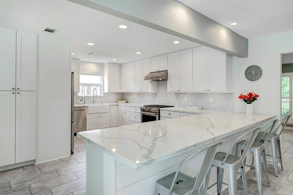Gleaming quartz countertops, farmhouse sink and sleek stainless steel Kitchen Aid appliances. Also plenty of counter seating! Pantry to the left