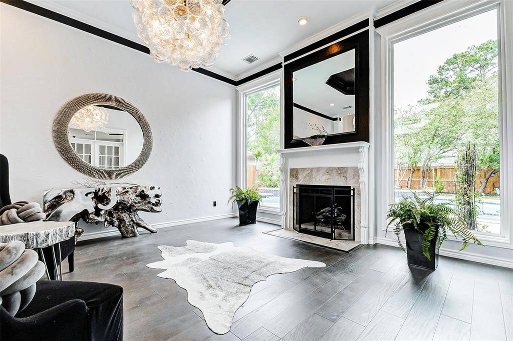 Bright formal living area with large windows and a cozy fireplace. The lush greenery outside provides a serene view.