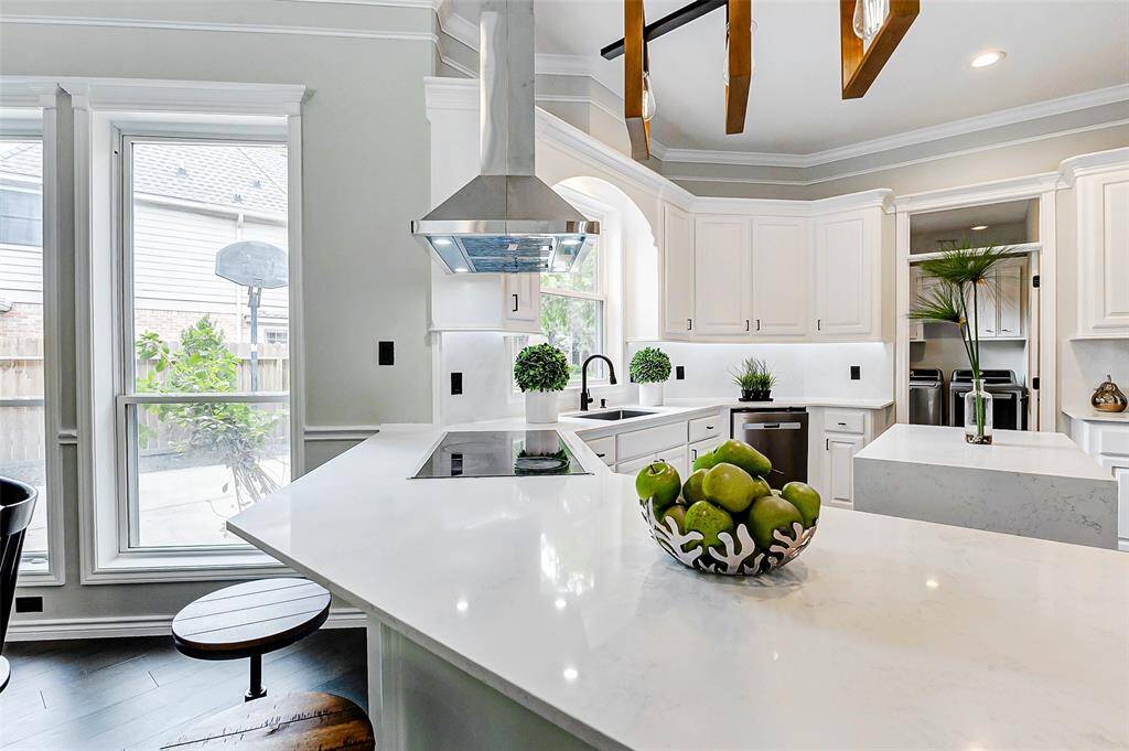 The bright and airy kitchen features sleek white cabinetry, modern stainless steel appliances, and a central island with quartz counter tops. Ideal for both cooking and entertaining.