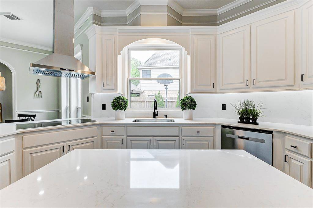 This kitchen boasts a modern design with a sleek waterfall island, stainless steel appliances, and under cabinet lighting.