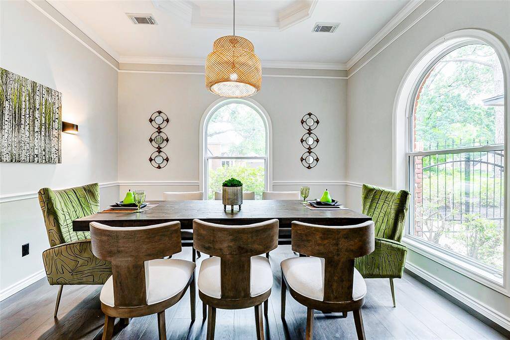 Bright dining room with large arched windows and elegant lighting, complemented by neutral accent walls.