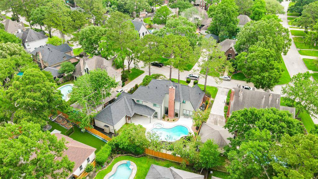 A charming suburban neighborhood with abundant greenery. The focal property features a spacious backyard with a swimming pool and ample privacy. The surrounding homes have well-maintained lawns and mature trees, creating a serene and inviting atmosphere.
