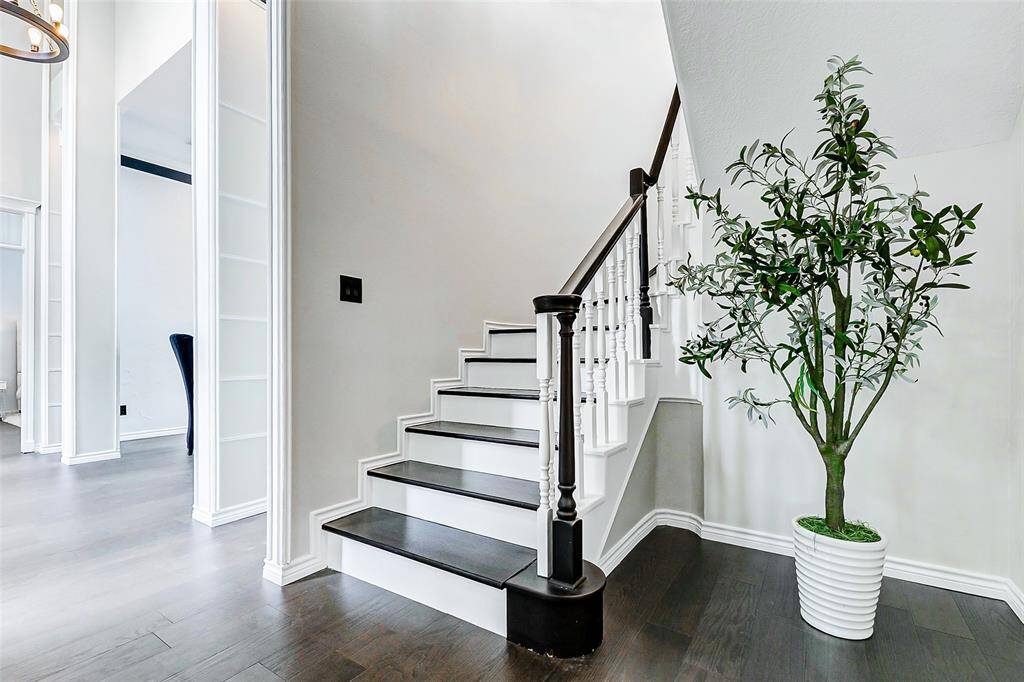 The stylish staircase featuring white railings and dark wood steps is elegantly hidden off the entryway.