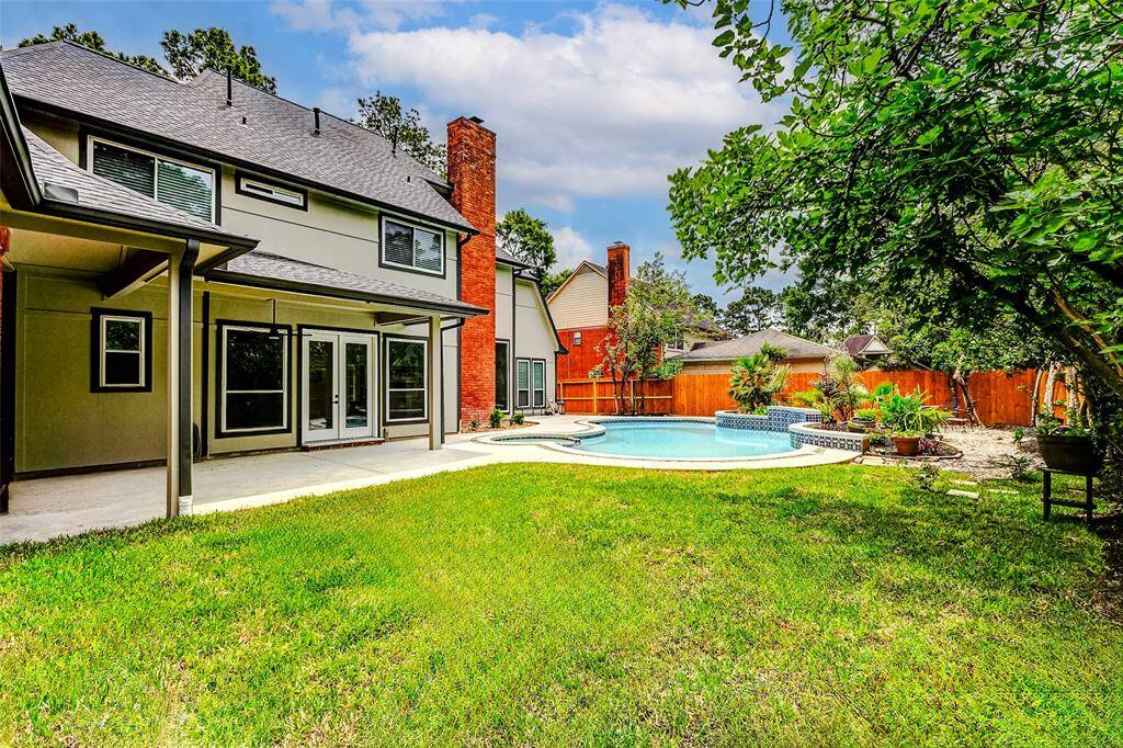 The home spotlights a spacious backyard with a well-maintained lawn, a covered patio area, and a beautiful in-ground pool with a spa. The area is enclosed by a new cedar wooden fence, offering privacy and a perfect space for outdoor entertaining or relaxation.