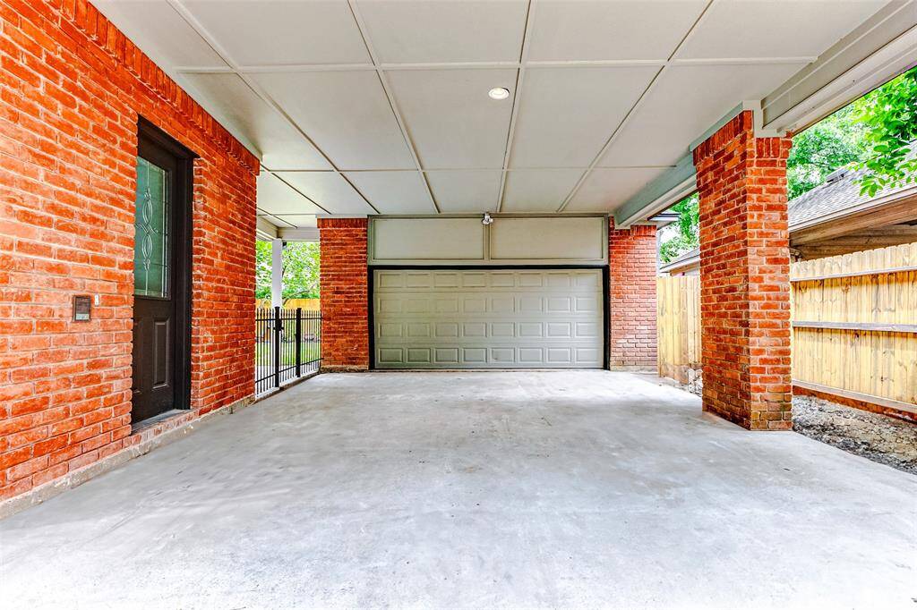Spacious porte cochère with a sturdy brick structure and full size attic for extra storage. It features an oversized garage and a wooden privacy fence, providing a secure and sheltered space for vehicles.
