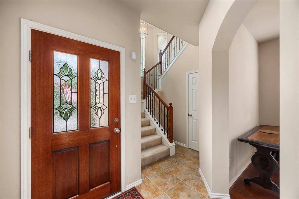 The wooden front door features decorative glass inserts with an ornate pattern, allowing natural light to filter in!