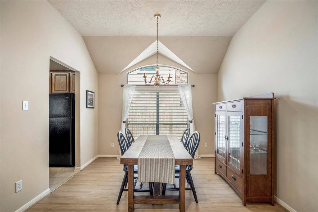 A closer look at the formal dining space reveals a large window with a transom above, allowing natural light to fill the room. The architectural details of the vaulted ceilings enhance the space, while the brand new vinyl plank floors add a touch of warmth and elegance.