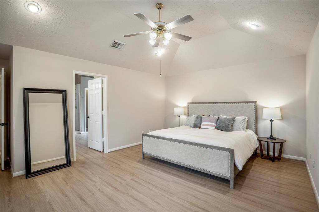 This angle of the primary suite offers a peek into the en suite bath, giving a sense of the seamless flow and privacy this spacious retreat provides.