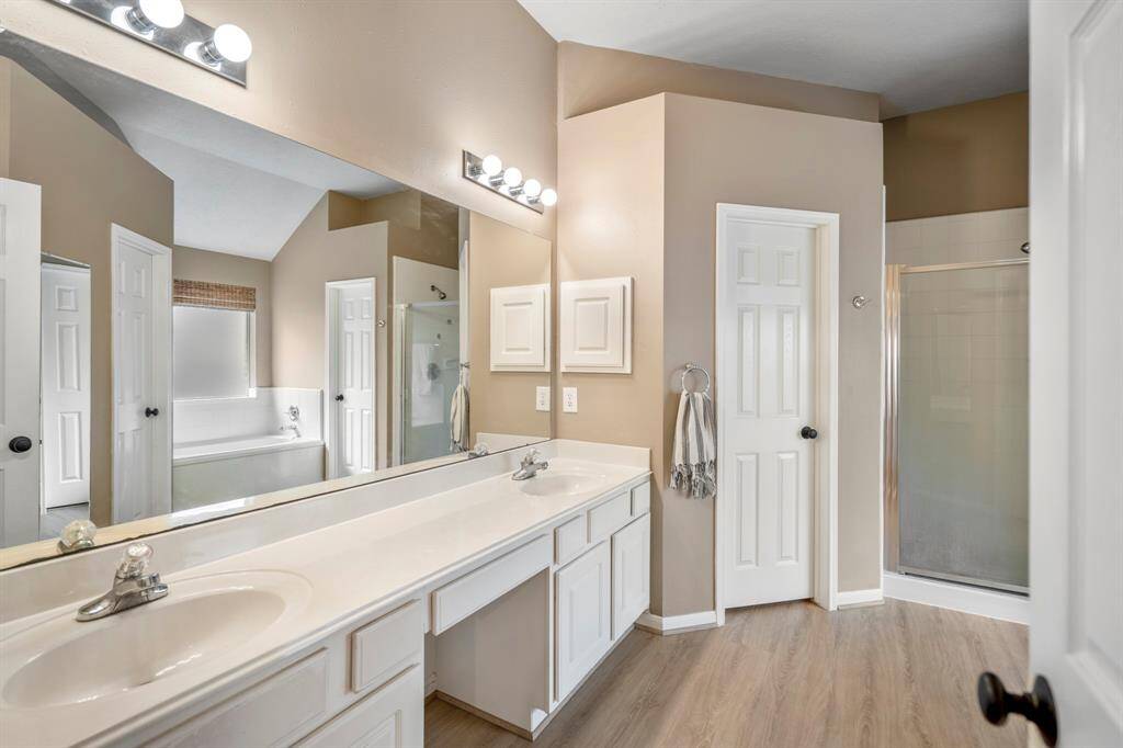 Stepping into the primary bath, you'll find dual sinks with a vanity space between. The soaking tub with a window above and separate shower are reflected in the mirrors, along with access to two walk-in closets and a private water closet for added convenience.