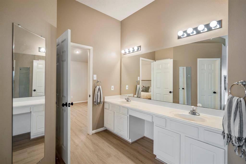 Looking back toward the dual vanities from near the soaking tub, you’ll see generous counter space, ample lighting, and a convenient vanity seating area between the sinks.