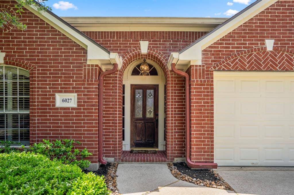 The inviting front porch features a beautiful wood door with decorative glass inserts, framed by transom and sidelight windows that fill the entryway with natural light.