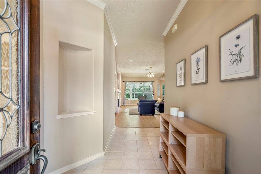 Step inside and take in the thoughtful details—crown moulding, tile flooring, and a decorative art niche with a trimmed shelf. Just off the entry, French doors open to a private home office, with the living room straight ahead.