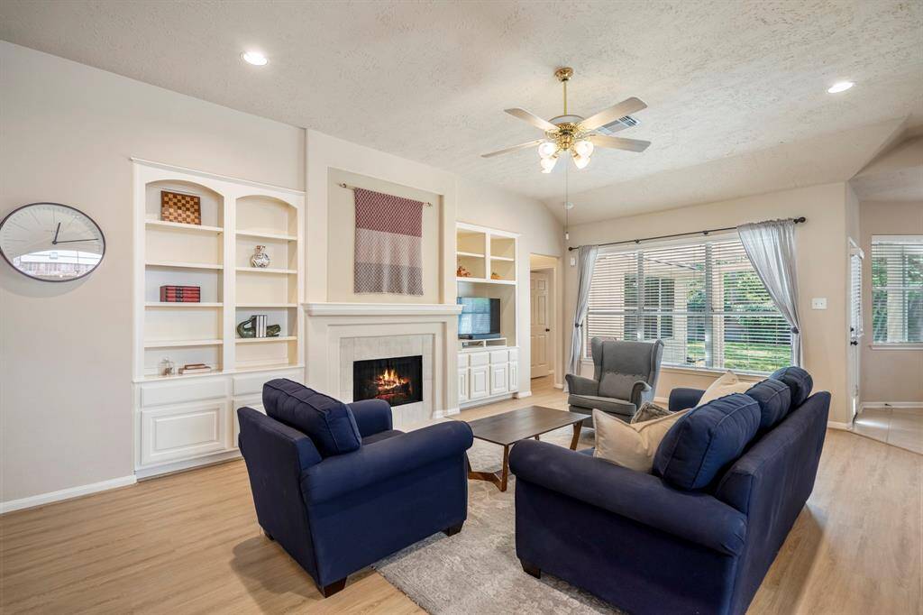 Another view of the living room highlights the vaulted ceilings, adding to the sense of space and openness. The fireplace with built-ins creates a stunning focal point, while the doorway to the right of the fireplace leads to the private primary suite, offering a peaceful retreat.