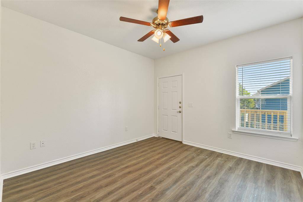 The master suite features fresh white walls, wood-style flooring, a ceiling fan with lights, and a window that brings in natural light. It includes an en suite bathroom & a door leading outside to the second-floor balcony.