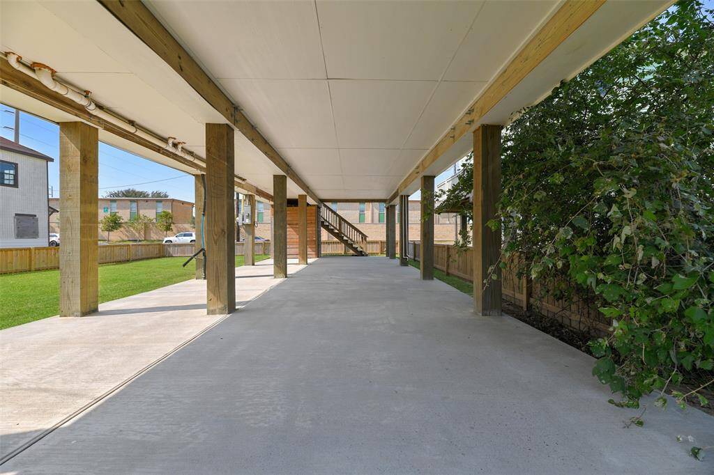 Beneath the home, a spacious covered carport area features a concrete floor, wooden support beams, and plenty of shadey space to enjoy the outdoors year round. It offers ample space for outdoor activities, with a well-maintained lawn, and a privacy fence.