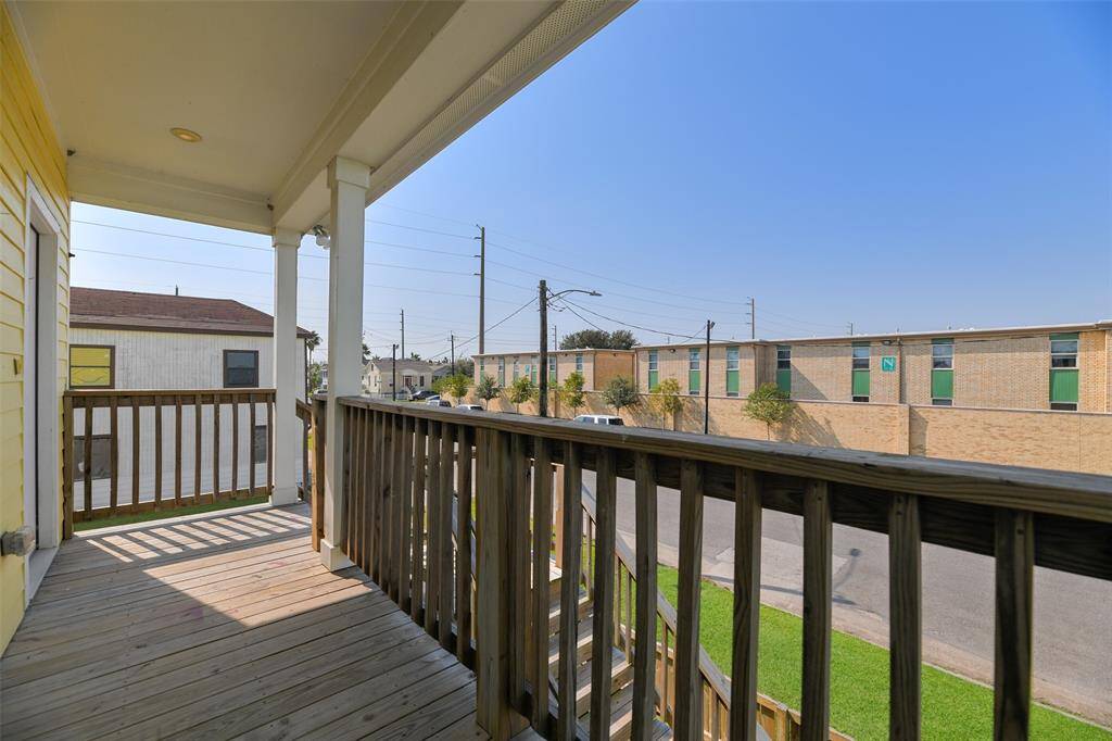 Enjoy your morning coffee on this covered wooden balcony with a view of the street and surrounding neighborhood. It's a cozy space for outdoor relaxation.