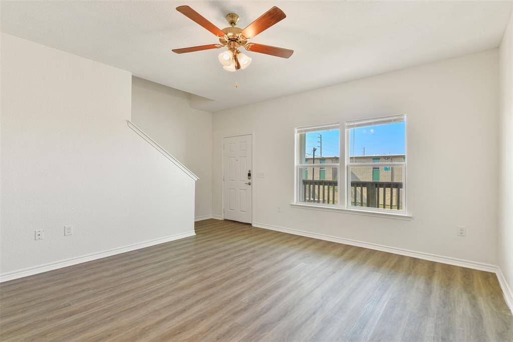 Bright living room with  easy maintenance wood-look vinyl plank flooring, a lighted ceiling fan, and large energy efficient double paned windows.