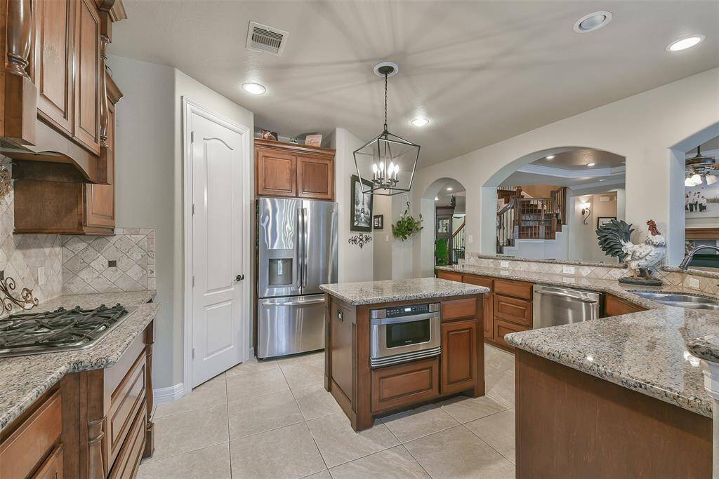 Island kitchen with stainless appliances, and granite counter tops. Gas cooktop. Custom cabinetry. Don't like the color? Easy, stain or paint them, they are solid wood! Built in microwave drawer! Enormous walk-in pantry!  Pendant lighting above the island compliments the coordinating one over the breakfast area.