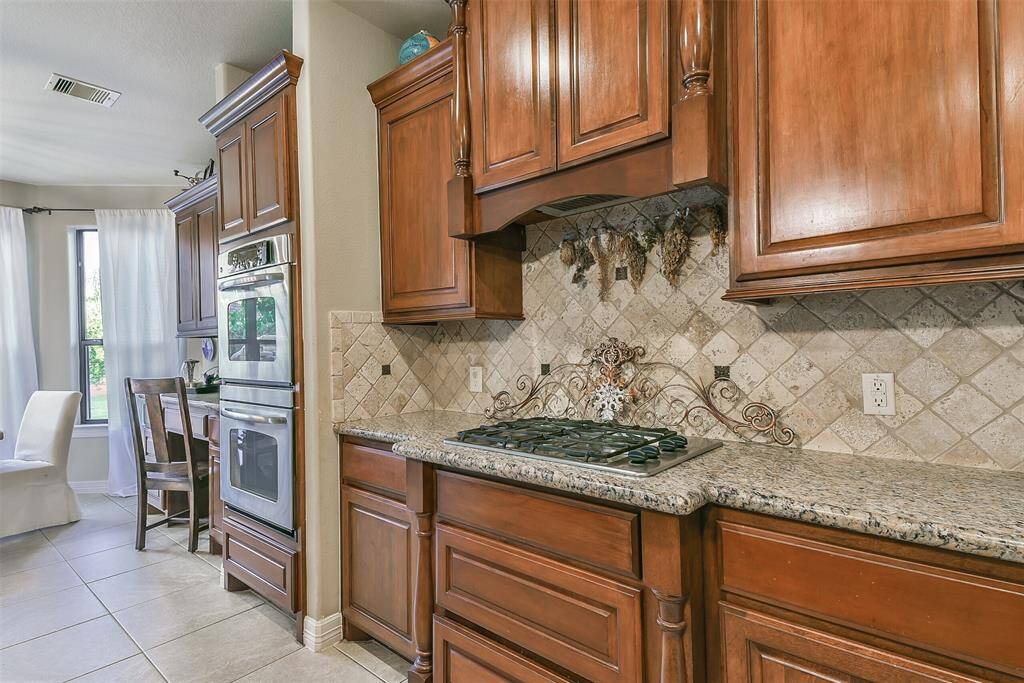 A kitchen made and designed for cooks!! Gas cooktop with pot drawers below!! Double ovens! And additional breakfast bar in the breakfast area. Travertine backsplash, with granite countertops. Neutral cohesive tile flooring in all main areas of the downstairs.