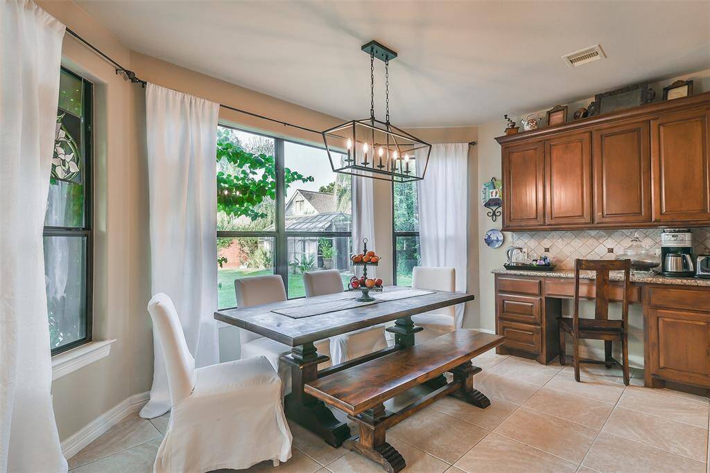 Large breakfast area surrounded with windows for natural lighting. Fabulous newly installed light fixture. Breakfast bar area with plenty of cabinetry! Views of the backyard greenspace as well as the pool from here!