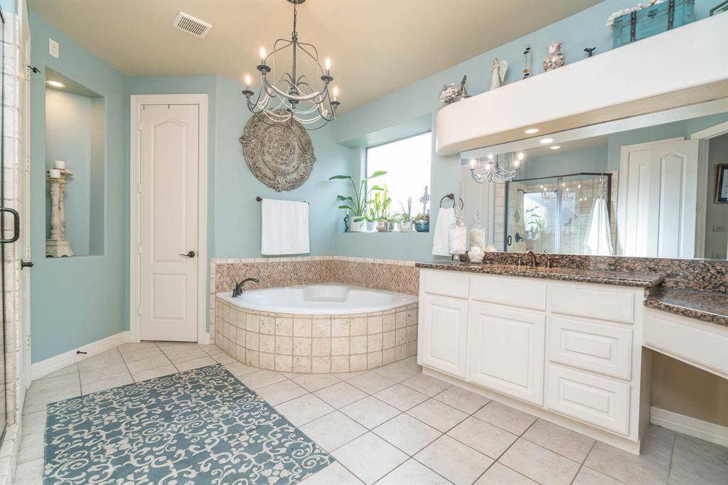 All downstairs doors are 8 foot tall two panel with lever handles. Granite double sink vanities plus a corner space. Large soaking tub beneath gorgeous chandelier wrapped in travertine tile, and oil rubbed bronze fixtures. Frosted glass window is perfect for orchid growing indoors! Lighted art niche/alcove. Walk in closet.