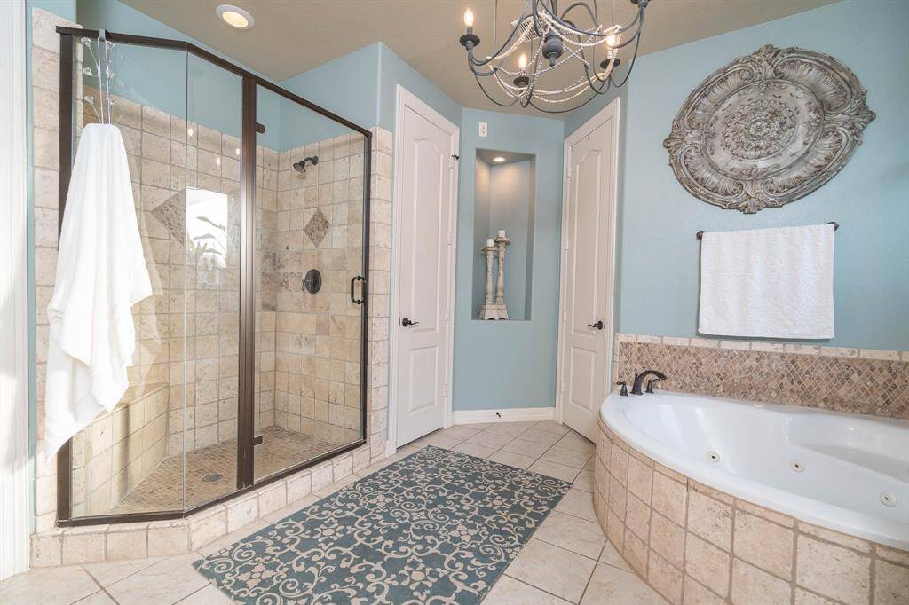 Shower surrounded with travertine tile and enclosure with oil rubbed bronze framing and hardware. Bench seating in the shower. Lighted art niches can be found in several places throughout the home.