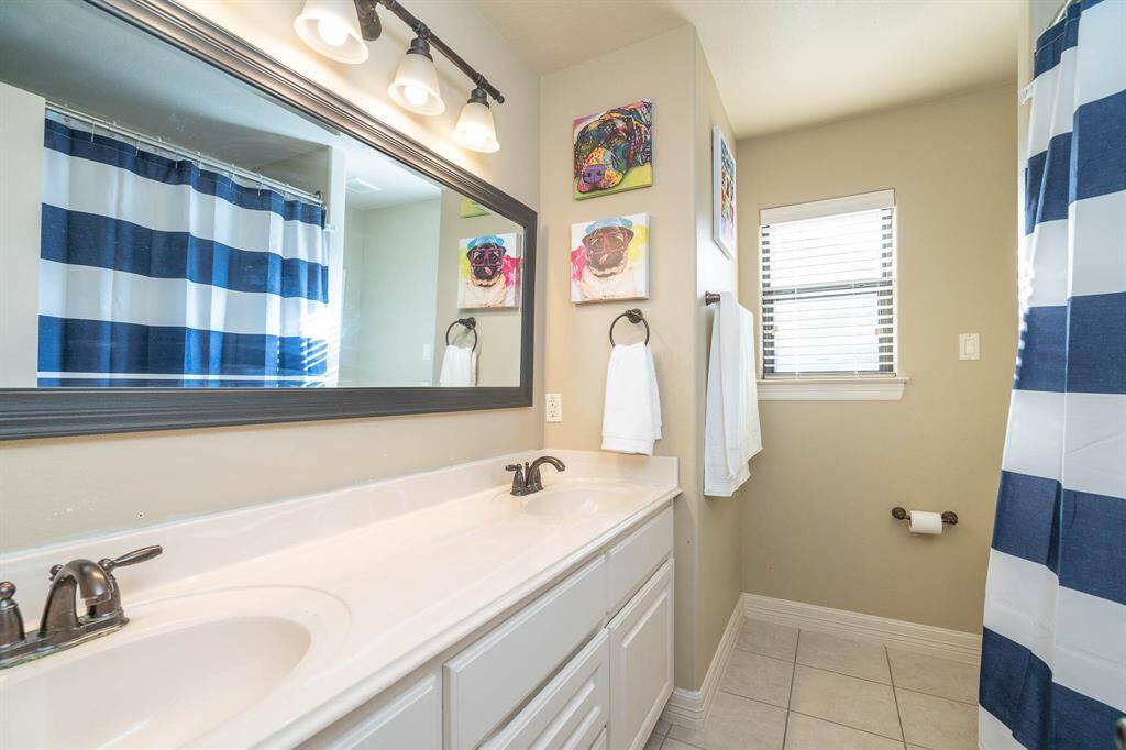 The first of 3 full sized bathrooms upstairs. This one has a tub/shower combo with beautiful tile and glass accent tiles. Double sink vanity and framed mirror.