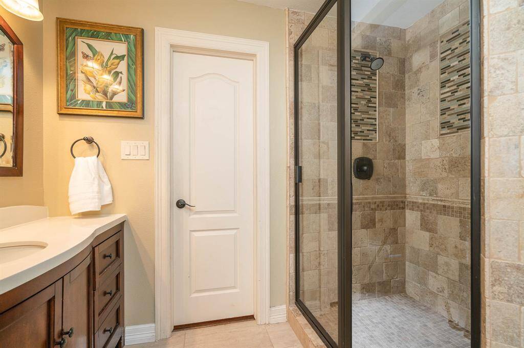 Bathroom attached to the chandelier bedroom. Floor to ceiling travertine shower with glass tile accents. Glass enclosure. This home has beautiful 2 panel doors throughout with lever handles.