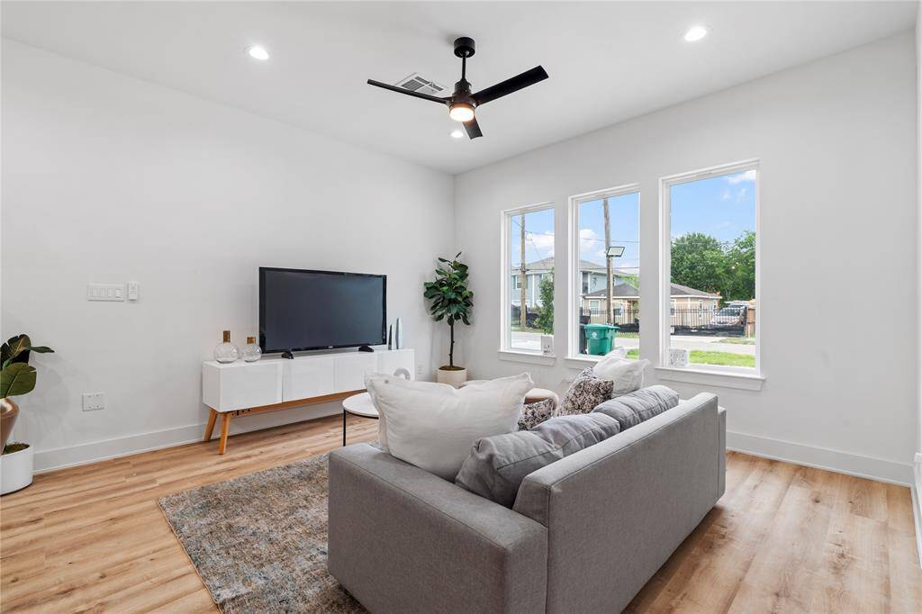 This modern and inviting living room exudes warmth and comfort with huge windows that flood in natural light, offering a stylish and cozy space to unwind and feel at home.