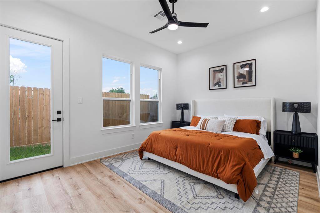 This primary bedroom showcases high ceilings, large windows that invite natural light, and a private outdoor access door, creating a bright and airy retreat.