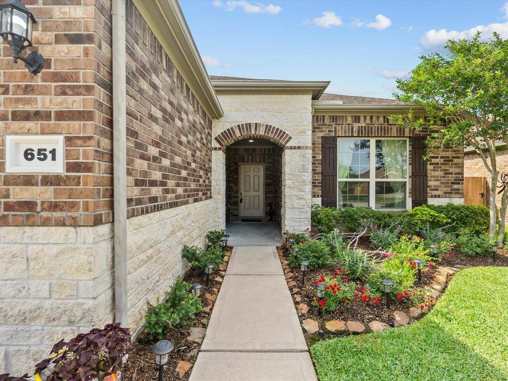 Absolutely charming and welcoming front porch entry featuring stone architectural details and fresh spring flowers!