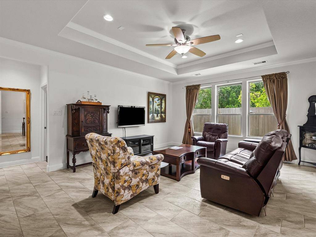 Wide open living room with tray ceiling also has crown molding and large windows for a view of all the trees!